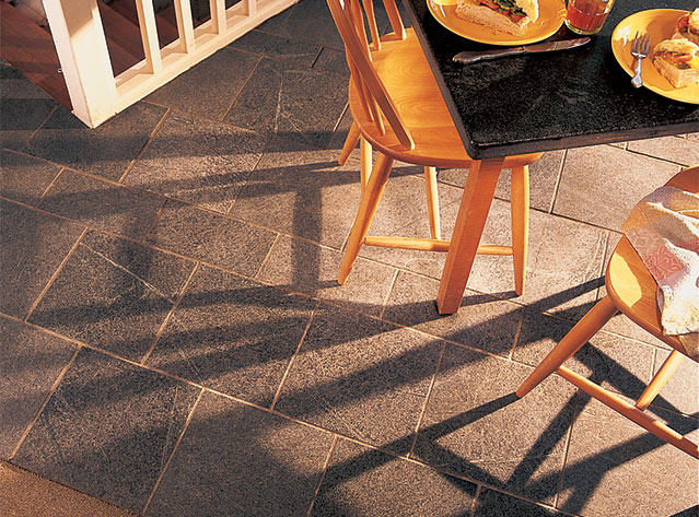 A Vermont Soapstone floor is light blue-gray with subtle veining. The oiled table is nearly black with the light veins in high contrast.