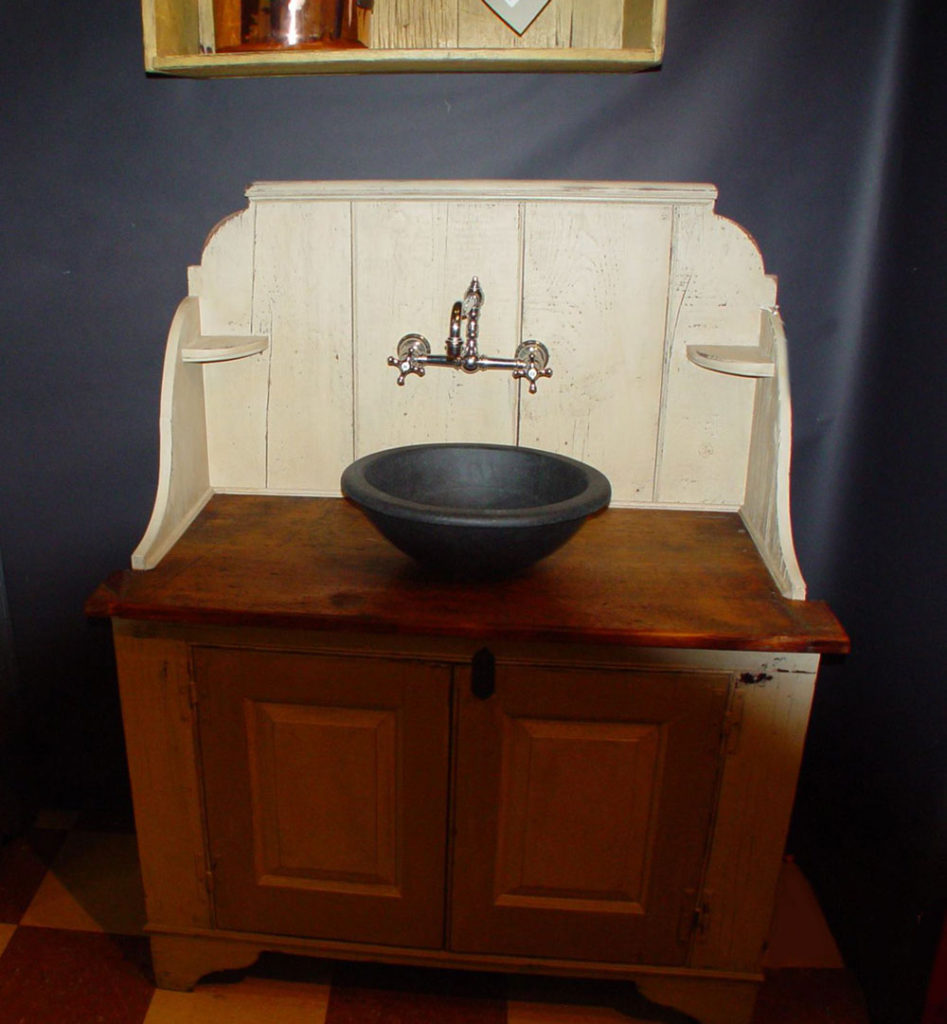 A Vermont Soapstone Cooper sink used as a basin on an antique cupboard makes this unique bathroom vanity one-of-a-kind.