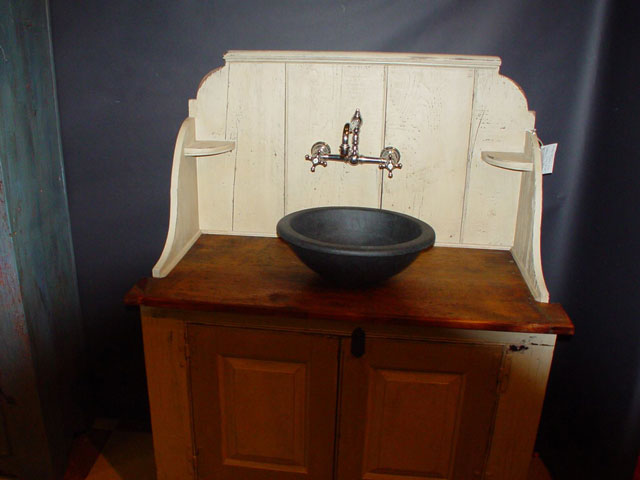 A Vermont Soapstone Cooper sink used as a basin on an antique cupboard makes this unique bathroom vanity one-of-a-kind.
