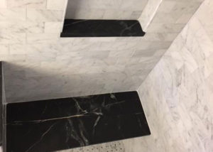 Dark Vermont Soapstone accents for the seat and inset shelves create the perfect accent to this marble shower surround.
