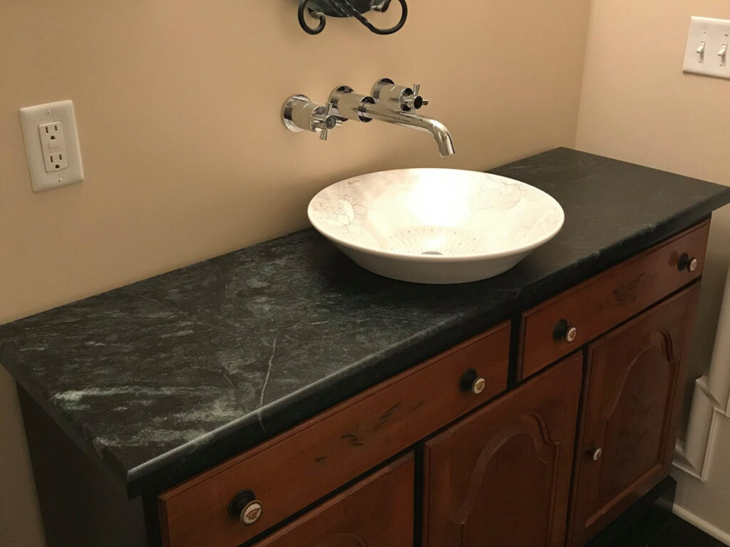 Vermont Soapstone countertop compliments delicate painted basin sink.